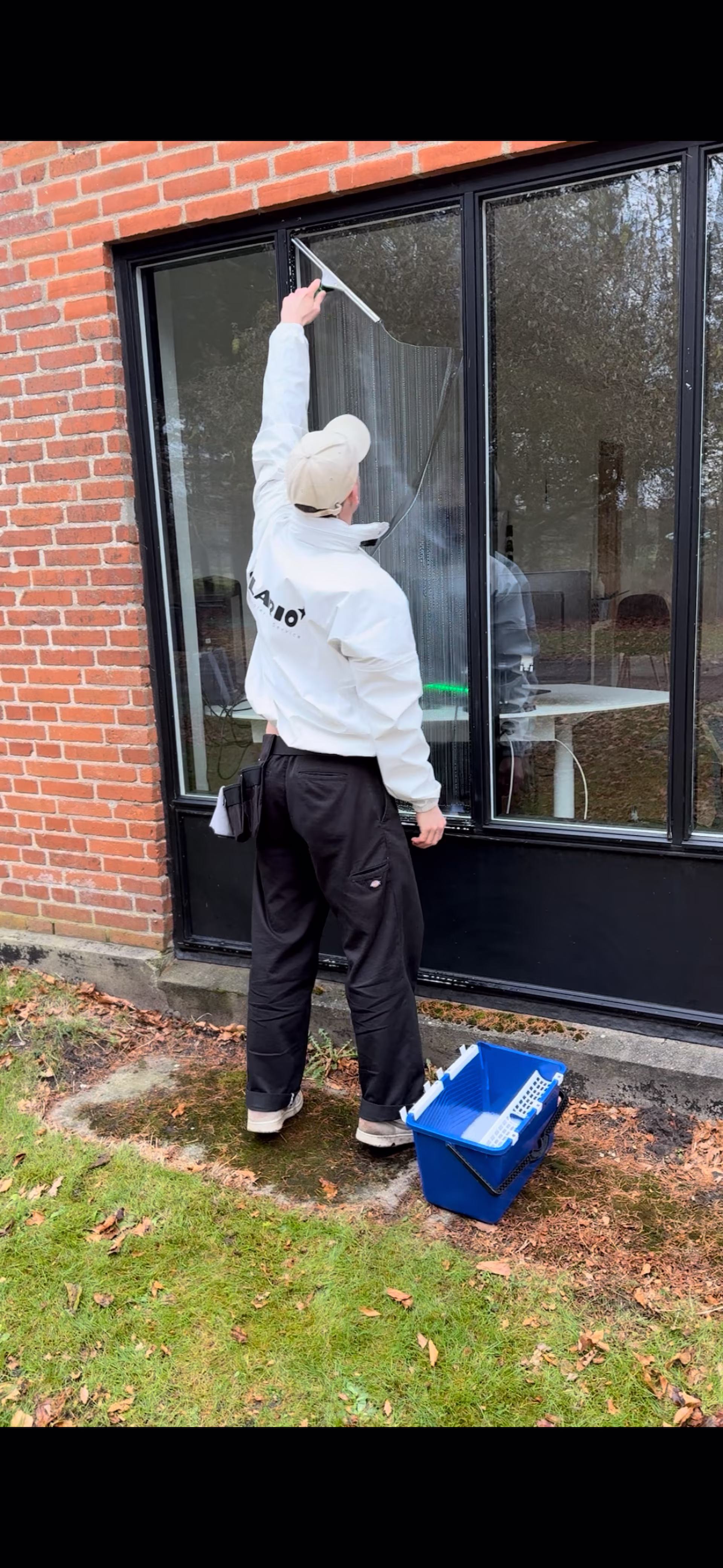 Professionel vinduespudser i arbejde med spand og udstyr